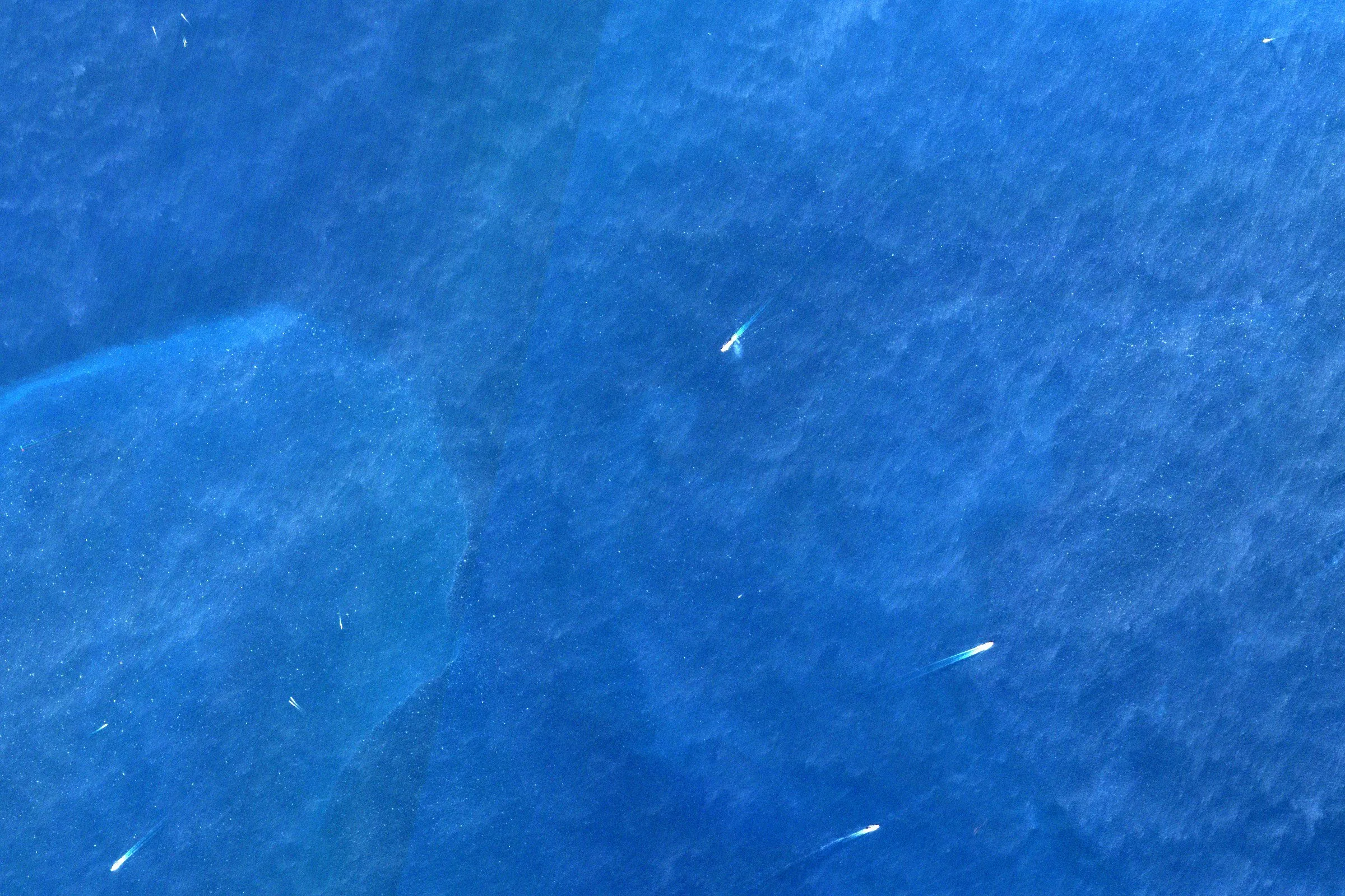 Satellite view of ships crossing open blue water in the Strait of Hormuz