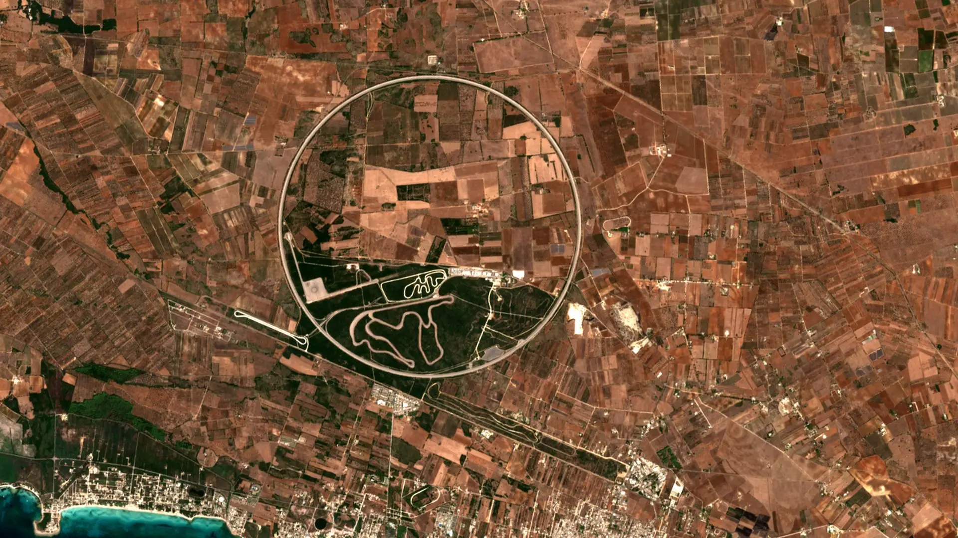 Sentinel-2 image of the Nardò test track in Puglia, a ring about 4 km across among red-brown fields and olive groves, with the Ionian coast in the bottom corner. The Nardò test track, Puglia, Italy, 5 September 2026