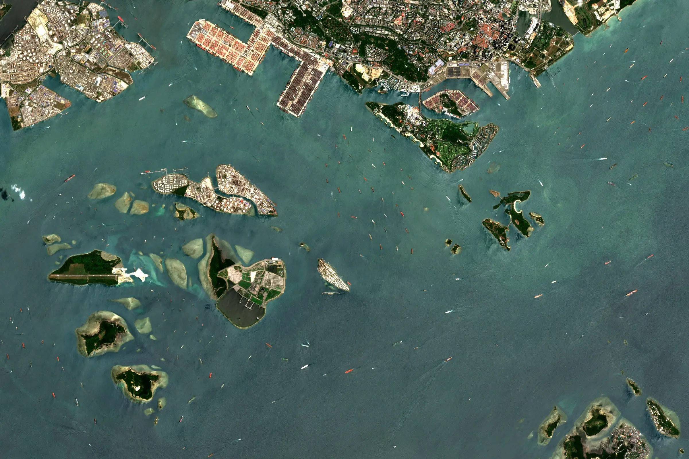 Satellite view of many ships at anchor in the Singapore Strait beside the container port
